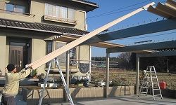 垂木で養生したタイトフレームの上を滑らせながら折半屋根材を持ち上げます。